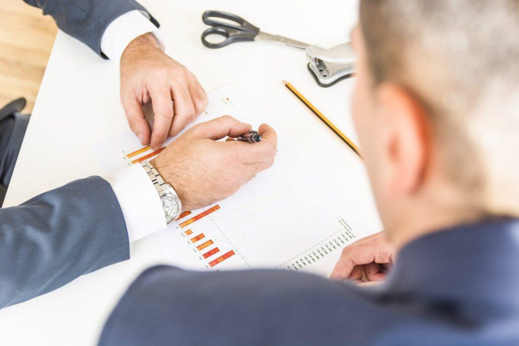 Two business professionals analyzing bar charts and financial data during a meeting, symbolizing the advantages of transfer pricing.