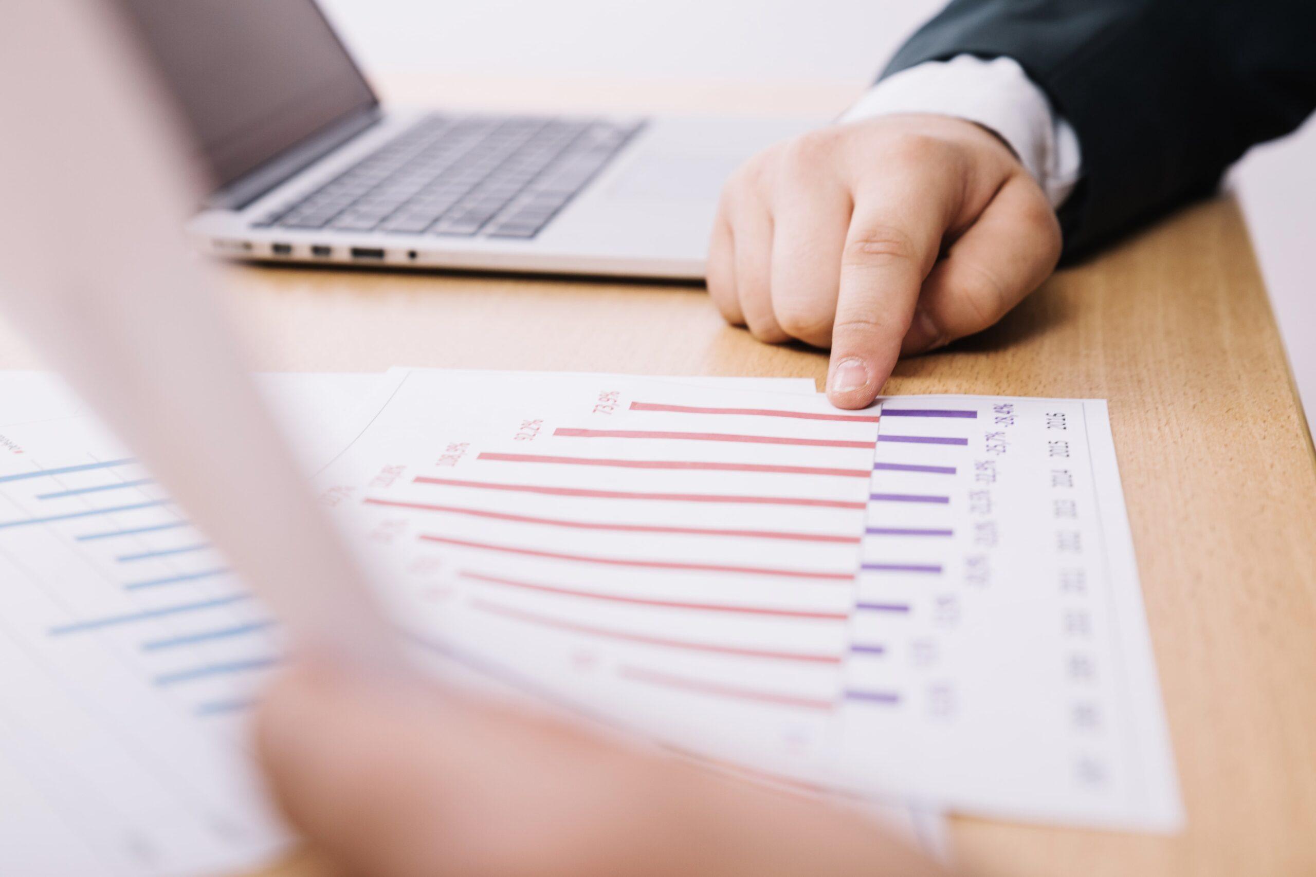 Businessperson pointing at financial charts during a transfer pricing audit with a laptop in the background.