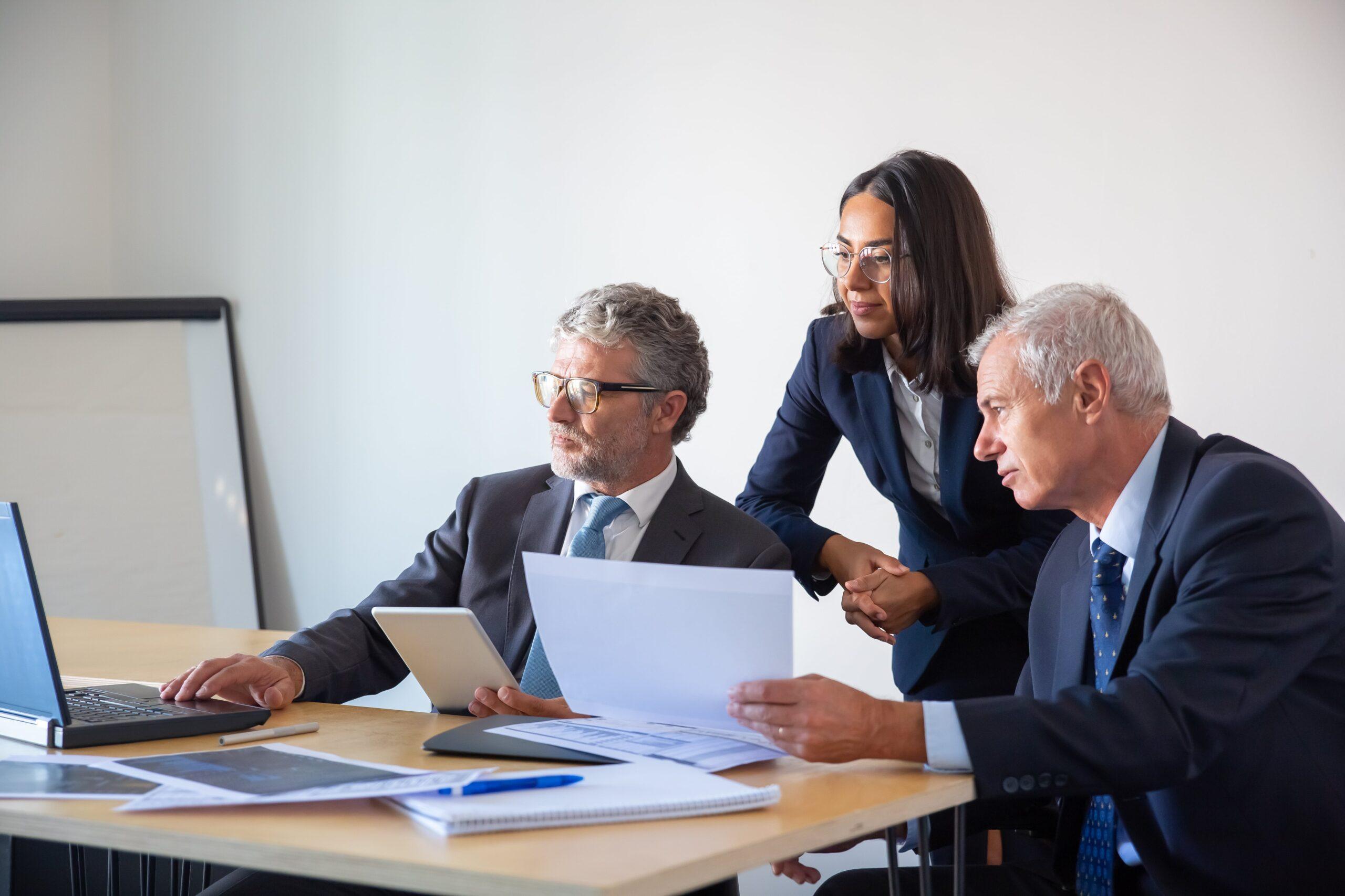 Three business professionals reviewing printed documents, representing transfer pricing documentation requirements.